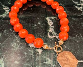 SOLD; polished coral 3/4" bead necklace with gold spacer inserts and attached vintage locket; 18"length