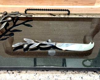 $100; black natural stone cheese board with metal leaf handle and matching cheese knife by Michael Aram.