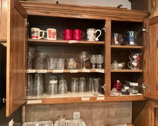 Cabinet in kitchen is full with cups, sets of glasses, pitchers, measuring cups, and so much more!