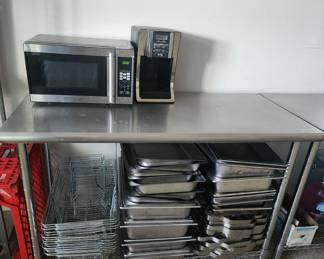 More stainless steel prep tables, microwave, coffee maker, and buffet trays with rack stands.