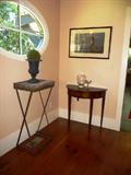 One of a pair of Antique iron stands from Detroit Garden Works, along with a mahogany demilune by Bombay