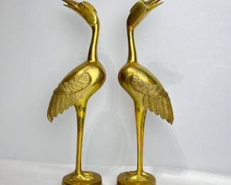 A pair of stunning vintage brass crane statues, tall and slender figurines feature intricate feather detailing and a graceful posture that capture the beauty of these majestic birds.