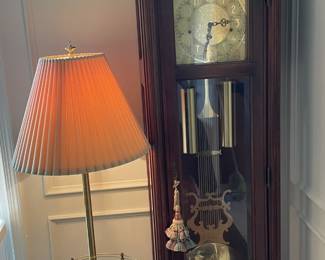 Floor lamp with glass table and grandfather clock.
