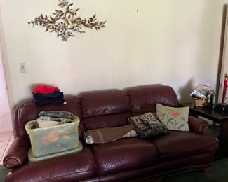 leather sofa, pillows, bin of scarves, wall decor
