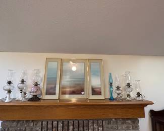 Oil lamps and sunset pictures on fireplace mantel