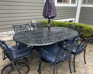 Cast aluminum patio table with four side chairs and two and rocker armchairs with umbrella