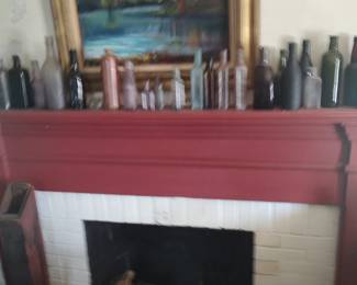 Part of a large collection of medicine and beverage bottles. One of the many paintings available is featured over the mantle.