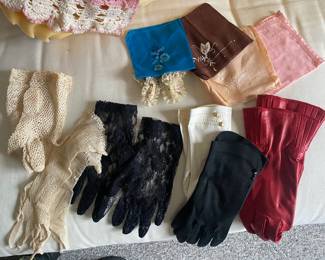 Wide assortment of gloves and crocheted doillies and vintage dresses too