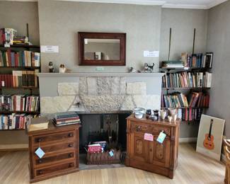 Front of Fireplace photo. Cabinet on left for sale. Vintage and antique books. Metal feather and shamrock planter. Guitar poster. Mirror. Collie figurines. Pottery. (small cabinet on right Not For Sale)