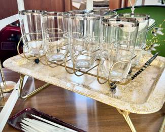 Two of two vintage metal glass/barware caddies and 1960s gold collapsible serving tray. Also pictured are set of tiny vintage square candles
