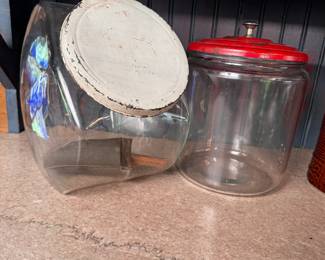 Two glass canisters with vintage metal lids and a metal scoop with wood handle, tallest is 10"