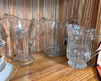 Group of EAPG clear glass pitchers, tallest is 9"H