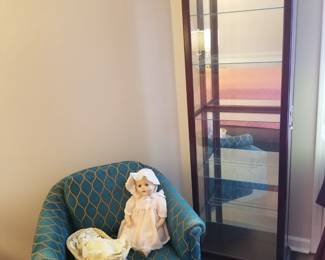Mahogany display cabinet, turquoise club chair. 