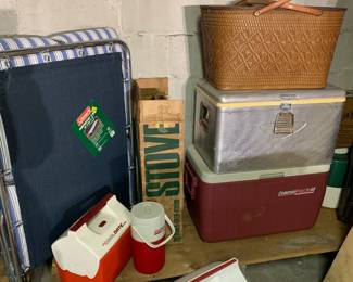 Outdoor gear, including vintage picnic basket in perfect condition, coolers, a campstove, and a brand new cot.