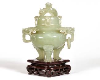 CHINESE CARVED JADE CENSER | Lid with a sinuous dragon and three mounts with carved rings, the censer with two foo dogs and reticulated openwork scrolls with carved ring raised on tripod legs with carved feet, and a conforming carved wood base; in original presentation box (14.25 x 9.5 x 6.5 in.)
l. 5 x w. 4 x h. 6.25 in. (jade)
