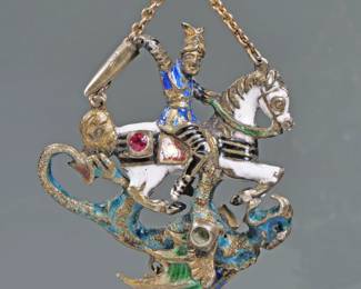 ENAMEL DECORATED ARTICULATING KNIGHT & DRAGON PENDANT | Manner of Faberge; designed as an enameled knight on horseback (possibly St. George) wearing a winged helmet and wielding a sword intertwined with a dragon with articulating wings, mounted with one ruby and one emerald and suspending a single seed pearl, hanging from a fine link chain. 20.8g - l. 1.75 in.