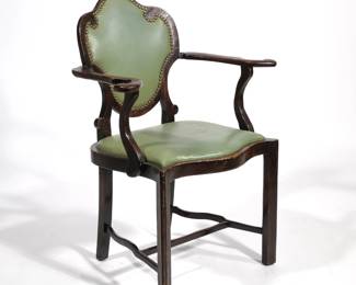 TRANSITIONAL ART NOUVEAU CARVED ARMCHAIR | Having a riveted leather back with ornate carved scrolls and curved hand-holds; leather cushion raised on carved wood legs with sinuous H-stretcher - l. 28 x w. 18 x h. 36 in.
