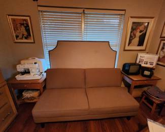 futon fold-out sofa, upholstered headboard standing behind the sofa, singer sewing machine, portable TVs and more