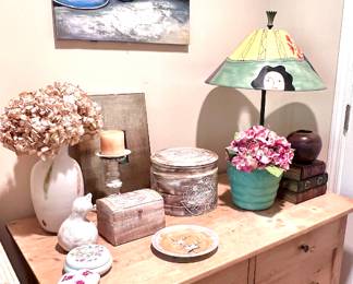 Dresser drawers, artsy lamp & many different ceramic pots, wooden box & ceramic vase. Art work hanging above. 