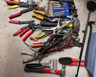 Assortment of hand tools including wire cutters, pliers, wrenches, pry bar, punches, magnet