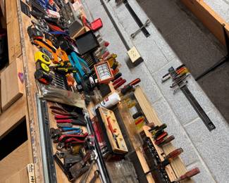 Group of workbench tools including screwdrivers, tape measures, magnetic tool strips, light, wrenches, hardware drawers