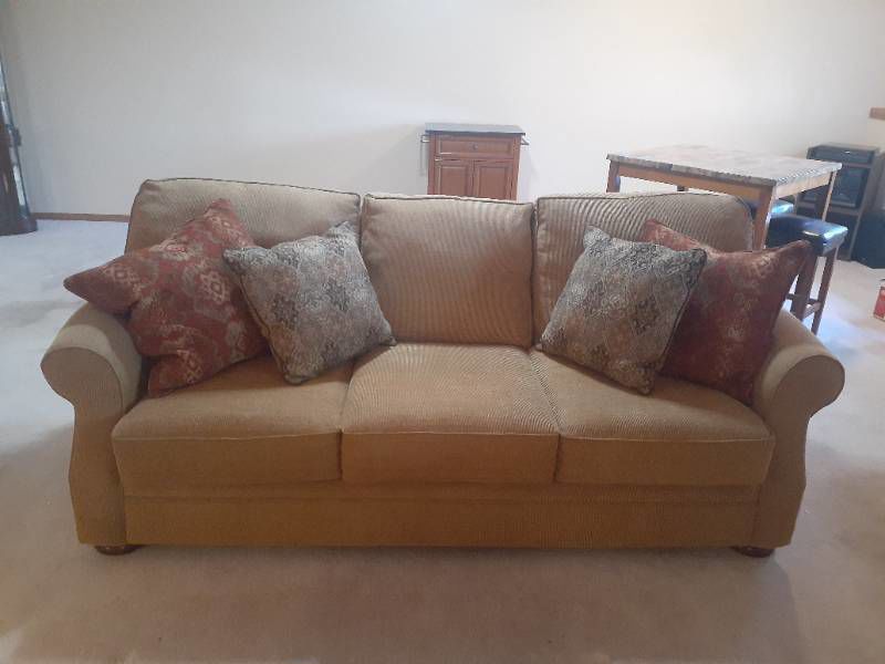 Mitchell sofa. 70 inches. Wheat colored with throw pillows. Matches lot 1001. Located in basement