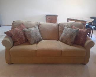 Mitchell sofa. 70 inches. Wheat colored with throw pillows. Matches lot 1001. Located in basement