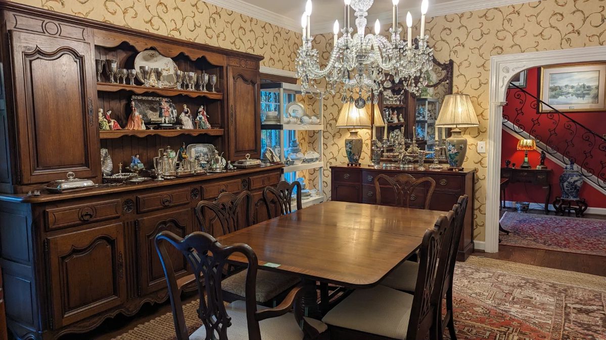 Beautiful dining room, with 1940's banded mahogany dining table, with two leaves, by Cassard, Romano Co., Inc., NYC, antique French oak hutch, 1940's mahogany buffet, by Drexel, antique English crystal chandelier, from 1900, segmented wall mirror,  pair of cloisonne table lamps, Persian Heriz rug atop a sisal rug and four sets of china. 