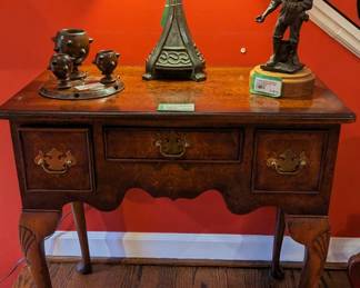 Close-up of the English burl walnut Queen Anne style writing desk, antique English wooden smoking set, Arts & Crafts bronze table lamp, w/glass shade, illuminated.