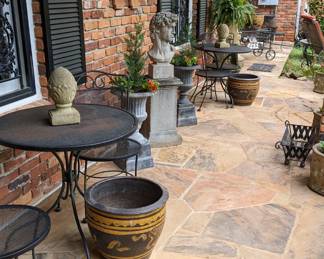 Front porch that invites you to sit  a spell! There's a pair of small, round wrought iron outdoor cafe tables, with pair of side chairs and a pair of glazed terra cotta planters, with dragon motif.