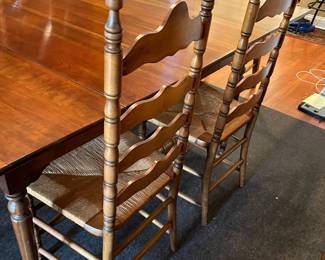 Gate legged Mid-Century Antique drop leaf cherry dining table w/ turned style legs. Total of 6 legs. 6 Ladder Back rush seats Chairs. 2 end chairs, 1 captain. 44"x26"-74"x29.5" (2 additional leaf inserts 12" ea) w/ Hagerty table leaf protectors bags and felt table top protectors.  (275 table, 30 a chair)