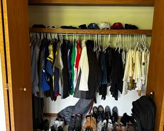 A closet filled with clothes, shoes, boots, hats and duffle bags! 