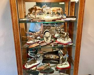 Curio full of knives and wildlife figurines.