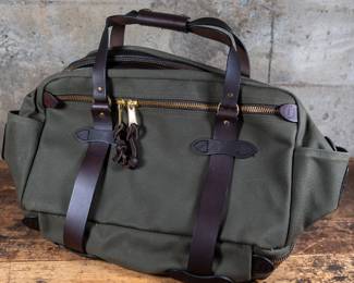 A Filson Medium Rugged Twill Duffle Bag in Otter Green. With Industrial-Strength lightly-waxed fabric. Brindle leather handles and an adjustable brindle leather shoulder strap. Heavy-duty brass zippers. Comes with 4 Filson luggage locks and key sets. New Condition.
