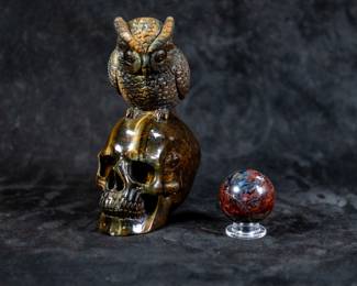 A skull carving with an owl on top, and a small sphere, both made of Hawkseye. Dimensions of the skull are included.
