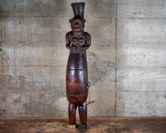 A Songye Fertility Statue depicting a pregnant woman and a door on her belly with a face inside. Originating from the Songye people who live in the central Democratic Republic of Congo. The statue's right foot had broken off.
