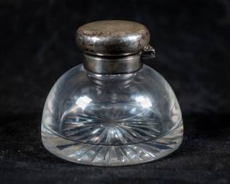 An inkwell with a sterling silver lid, manufactured by John Grinsell & Sons in 1894. The lid has London hallmarks with the maker and date information.
