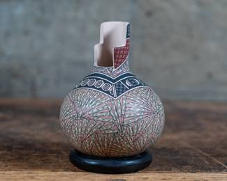 A small vase with colorful geometric painted designs, from Mata Ortiz. Comes with a black stone ring base.
