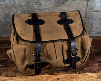 A Filson Medium Field Bag, in Tan color. Storm flap with double buckle-closure and a reinforced base. Comes with an adjustable 46" long bridle leather strap with a pad.
