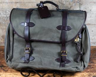 A Filson Large Rugged Twill Carry-On Bag in Otter Green Color. With brindle leather dual clasps, a leather luggage tag, and heavy-duty brass zippers. Lightly used condition.
