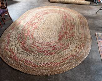 A large oval shaped hand-braided farmhouse style area rug. Two 6" sections of stiching have come undone but appear to be repairable.
