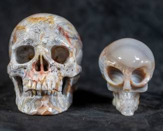 A Crazy Lace Agate carved human skull & an alien skull carved out of Agate. Dimensions for the larger skull are included.

