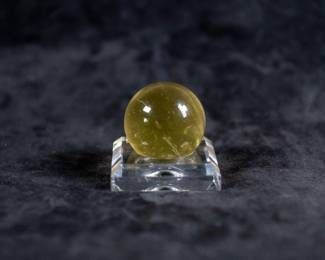 A genuine Tektite glass sphere from the Libyan Desert, with very fine quality finish and rich greenish yellow color. Libyan desert glass Tektites are formed by intense heat produced by meteoric aerial bursts over sand dunes in Western Egypt approximately 28.5 million years ago. Comes with a Certificate of Authenticity from G.M.M. Inc.
