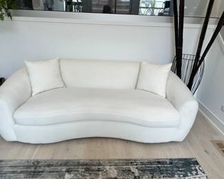 Elevate your living space with this elegant off-white bouclé curved sofa, a perfect blend of style and comfort. Its luxurious texture and inviting silhouette make it a standout piece in any decor. The sofa features plush, deep seating upholstered in soft bouclé fabric, known for its cozy, looped texture that is both durable and comforting to the touch. The gentle curve of the sofa not only enhances the aesthetics of the room but also encourages conviviality, making it an ideal spot for social gatherings or tranquil relaxation.