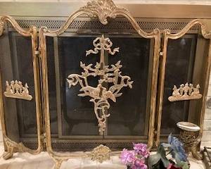 Elegant brass decorative fireplace trim surrounding a black iron screen. 