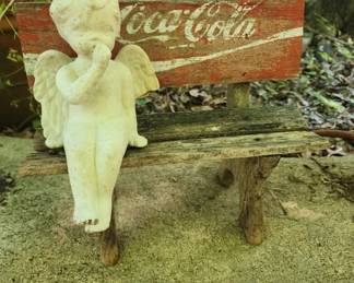 Ceramic angel on antique coca cola bench

