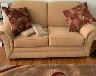 Light gold/tan love seat 64 inches long to outside arms and 47 inside, 37 inches deep with pillows
