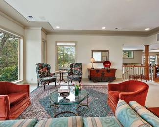 Two Rust/Red Velveteen Club Chairs. Large Persian Carpet. Patterned Sofa. Two Wing Back Floral Chairs. Traditional Side Table. Glass and Wrought Iron Octagon Coffee Table. 