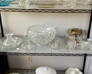 Top: Vintage Aqua Italian Ruffled Edge Bowl, Rieske-Crisa “Moderno” Crystal Punch Bowl and Cups, Krosko Poland Crystal Footed Trifle Bowl.
shelf 2: AH Early American PresscutbTorte Plate, Cake Plate and Stand, Smith Glass “Daisy and Button” Vintage Punch Bowl, McKee Glass “The Concord Pattern Glass Punch Cups, Solid Brass Punch Bowl Stand and McKee Glass Open Sugar & Creamer
Shelf 3: Secla White Porcelain Soup Tureen w/Ladle, Effetti D’Arte Pedestal Bowl and Chop Plate,  Ironstone Condiment Server and Chrome Caddy

