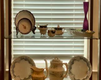Mid-Century Modern Walnut Etagere’ with 4 Smoke Glass Shelves.  Top shelf: Vintage Amberina Glass Oil Lamp, Indiana Honeycomb Patter Amber flashed red Dish, Amberina Pedestal Compote
shelf 2: Call Bob blue decorated China
Shelf 3:  Johnson Brothers, England”Sylvan” China.  Bottom Shelf: More Goofus Glass
